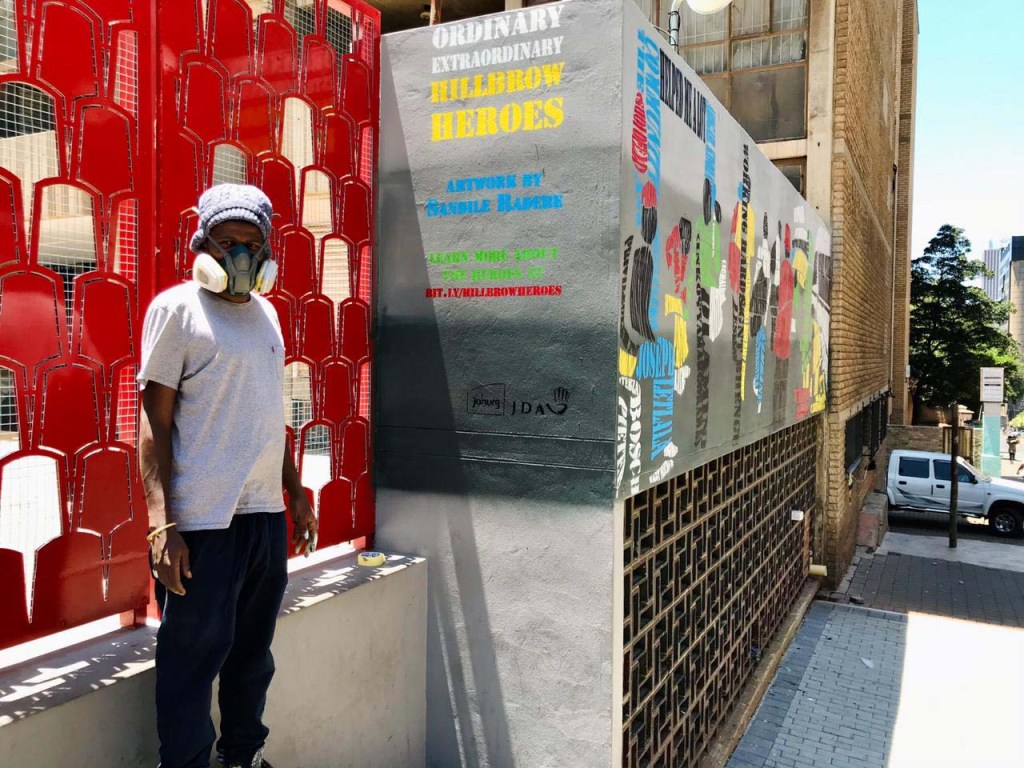 Wide shot of the Boundless City mural painted on the exterior wall of Hillbrow Theatre, showing the scale of the spraypainted text-based work in its urban context.