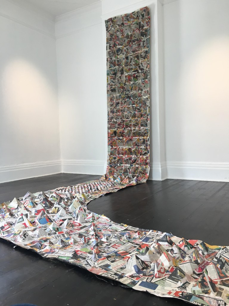 Newspaper installation titled "Amabheqe emihla ngemihla" (2023), featuring variable arrangements of printed material referencing isiZulu petroglyphs and their relevance in everyday life.