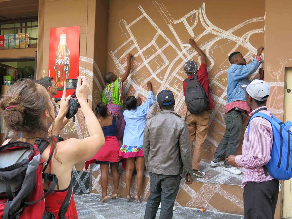 Interactive mural created with chalk, inviting public participation to redraw the city map, challenging apartheid-era spatial divisions in Cape Town.
