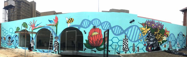 A vibrant mural featuring stylised depictions of South African flora and fauna. Bold colours and layered imagery blend with poetic text, created through a collaborative effort between mural artists, poets, and designers to celebrate biodiversity.