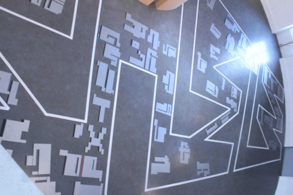 Mixed media installation transforming a circular gallery into a navigable sculptural maze inspired by Johannesburg’s urban fabric and graffiti language.