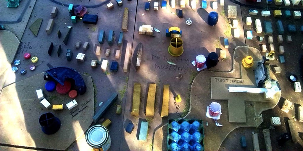 Public installation composed of colourful found objects arranged on a softwood contour map, created during a civic engagement intervention at Vrystaat Kunstefees 2016 in Bloemfontein.
