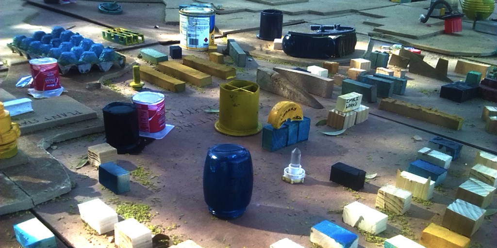 Public installation composed of colourful found objects arranged on a softwood contour map, created during a civic engagement intervention at Vrystaat Kunstefees 2016 in Bloemfontein.