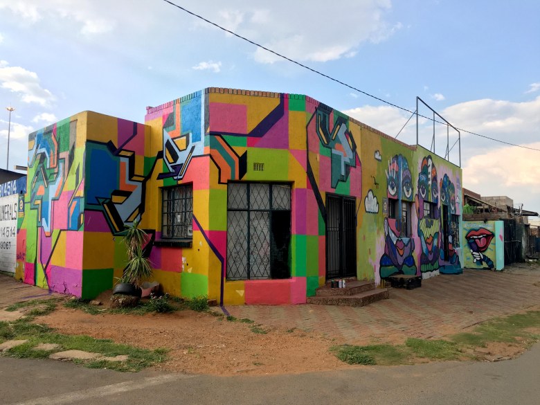 Collaborative spraypaint mural by Sandile Radebe and Bona Berlin, featuring abstract and figurative elements reflecting Johannesburg's urban landscape, located in Phefeni, Soweto.​